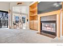 Cozy living room featuring a fireplace, built-in shelves, and access to an outdoor balcony with natural light at 1730 Crestone Dr, Longmont, CO 80504