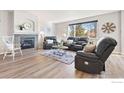 Sunlit living room with a fireplace, hardwood floors, and plush leather seating creating a cozy atmosphere at 1788 Alpine Dr, Erie, CO 80516