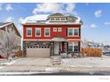 Inviting two-story red home featuring a stone-accented garage and a cozy front porch with a landscaped yard at 23593 E Chenango Pl, Aurora, CO 80016