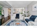 Bright living room featuring hardwood floors, neutral walls, white sofas, and a stylish blue-and-white rug at 23593 E Chenango Pl, Aurora, CO 80016