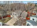 Aerial view of a home with a red fenced yard, mature trees, and a well-maintained lawn at 4185 Corriente Pl, Boulder, CO 80301