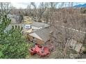 Aerial view of a backyard with a spacious red deck, lush trees, and a well-maintained lawn at 4185 Corriente Pl, Boulder, CO 80301
