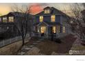 Charming two-story home with welcoming front porch, manicured lawn, and inviting sunset at 5735 Russell Cir, Frederick, CO 80504