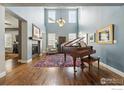 Elegant living room with hardwood floors, a fireplace, and a beautiful grand piano at 630 Benton Ln, Erie, CO 80516