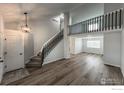 Inviting entryway with modern light fixture, staircase, and wood-look flooring at 1219 Cedarwood Dr, Longmont, CO 80504