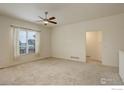 Spacious living room with neutral carpet, a ceiling fan, and large windows for ample natural light at 1540 Murrlet St, Berthoud, CO 80513