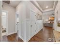 Bright hallway featuring hardwood floors, white wainscoting, and access to various rooms at 334 Rhubarb Dr, Berthoud, CO 80513