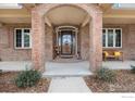 Inviting brick front porch with decorative door and a bench for relaxing at 3806 Singletree Ct, Mead, CO 80542
