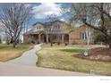 Lovely brick home with a curved walkway, lush lawn, and mature trees at 3806 Singletree Ct, Mead, CO 80542