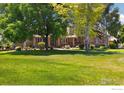 Beautiful home featuring mature trees, lush green lawn, and a welcoming brick exterior at 3806 Singletree Ct, Mead, CO 80542