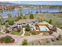 Aerial view of a large home with a pool, patio, and lake access, offering a private oasis at 4514 Hoot Owl Dr, Berthoud, CO 80513