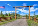 Grand entrance to 'Home Sweet Home' gate with custom wood accents, leading to a gravel driveway at 4514 Hoot Owl Dr, Berthoud, CO 80513