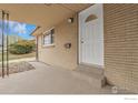 Covered front porch with a classic white front door and brick siding at 615 S Shoshone St, Denver, CO 80223
