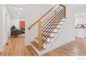Modern staircase featuring wood treads, white risers, and a sleek black metal railing, with hardwood flooring throughout the home at 6916 Hunter Pl, Boulder, CO 80301