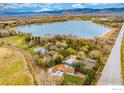 An aerial view showcasing the property, a picturesque lake, and the surrounding landscape at 7390 Ute Hwy, Longmont, CO 80503