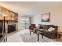 Inviting living room featuring a stone fireplace, neutral walls, and sliding glass door to a balcony at 8335 Fairmount Dr # 207, Denver, CO 80247