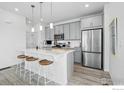 Modern kitchen boasts stainless steel appliances, gray cabinets, sleek counter tops, and an island with bar stool seating at 1365 Shale Dr, Erie, CO 80516