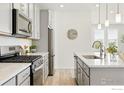 Modern kitchen with stainless steel appliances, grey cabinetry, and an island with a sink at 1365 Shale Dr, Erie, CO 80516