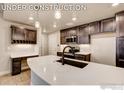 Modern kitchen features dark wood cabinetry, white countertops and stylish pendant lighting at 235 High Point Dr # 102, Longmont, CO 80504