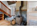 Cozy living room featuring a wood burning stove, wooden staircase, tile flooring, and exterior access at 286 S Rainbow Trl, Evergreen, CO 80439