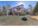 Expansive backyard with a deck, stairs, fire pit, and lush lawn, ideal for outdoor entertaining at 85 Kolar Ct, Erie, CO 80516