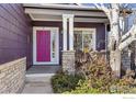 Inviting front porch with vibrant pink door, stone accents, and manicured landscaping at 85 Kolar Ct, Erie, CO 80516