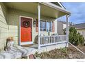 Cozy front porch with seating area, decorative wreath, and charming curb appeal at 1026 Red Oak Dr, Longmont, CO 80504