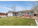 Inviting single-story home with a well-kept lawn, mature trees, and a cozy front porch bench at 103 Division Blvd, Platteville, CO 80651