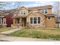 Charming two-story home featuring a stone facade, covered porch, and well-maintained lawn at 14214 Waterside Ln, Broomfield, CO 80023