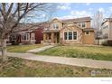 Charming two-story home featuring a stone facade, covered porch, and well-maintained lawn at 14214 Waterside Ln, Broomfield, CO 80023