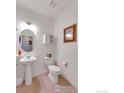 Cozy half-bath with pedestal sink, toilet, and decorative mirror and artwork at 1800 Vantage Pkwy, Berthoud, CO 80513