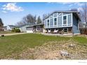 Two-story blue home with an attached garage, front lawn and a cozy seating area at 205 Lucerne Dr, Lafayette, CO 80026