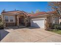 Charming single-story home featuring a red tile roof, stone accents, and a two-car garage under a bright blue sky at 2977 Dunes Ct, Longmont, CO 80503