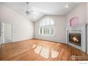 Bright living room with hardwood floors, vaulted ceilings, fireplace, and a large arched window with plantation shutters at 2977 Dunes Ct, Longmont, CO 80503