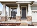 Inviting front porch with large pillars, stylish bench and house number on display at 5861 Mt Shadows Blvd, Firestone, CO 80504
