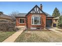 Charming brick home with a Tudor-style accent, bay window, and well-kept lawn at 865 Holly St, Denver, CO 80220
