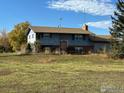 Two-story home under a partly cloudy sky featuring a front porch and mature trees at 937 Glenview Dr, Berthoud, CO 80513