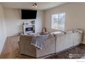 Cozy living room with a fireplace, large sofa, and natural light from a window at 1022 Wagon Bend Rd, Berthoud, CO 80513
