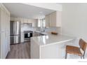Modern kitchen with stainless steel appliances, white cabinets, quartz countertops, and breakfast bar at 1085 Fairway Ct # A, Boulder, CO 80303