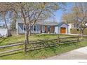 Front exterior of home with fenced yard, mature trees, brick accents, and wooden garage door at 1529 Washington Ave, Louisville, CO 80027