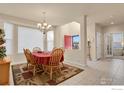 Elegant dining room with a chandelier, large windows, and a red-covered dining table at 1533 Bellflower Dr, Brighton, CO 80601