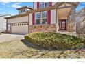 Well-maintained two-story home featuring a stone facade, red shutters, and lush green landscaping at 1533 Bellflower Dr, Brighton, CO 80601