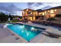 Backyard pool with outdoor seating, diving board and accent lighting at dusk at 2600 High Prairie Way, Broomfield, CO 80023