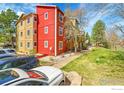 Multi-Gathering home showing red and yellow siding, surrounded by greenery, with car parking available in front at 2867 Sundown Ln # 106, Boulder, CO 80303