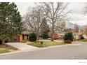 Suburban home with mature trees, well-kept lawn, and driveway leading to a two-car garage at 590 Yuma Cir, Boulder, CO 80303