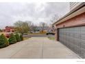 Long driveway leading to an attached garage, bordered by manicured hedges and a tree at 637 Millet Cir, Brighton, CO 80601