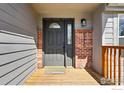 Inviting front porch with brick accents, wood planking, and a charming welcome mat at 9215 W 106Th Ave, Broomfield, CO 80021