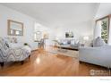 Open living room with hardwood floors, neutral furniture, and large windows, offering an airy and connected space at 10894 Depew Pl, Westminster, CO 80020