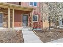 Inviting townhome entrance with concrete steps, a covered porch, and a blossoming tree at 1240 Wren Ct # I, Longmont, CO 80501
