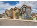 Charming street view of townhomes with varied colors and blossoming trees in a Gathering-friendly neighborhood at 1240 Wren Ct # I, Longmont, CO 80501